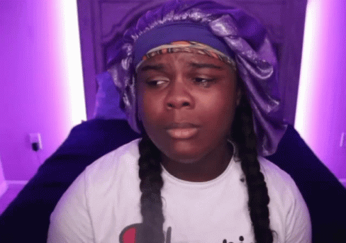 Woman in White Shirt and Purple Hat Sitting on Bed