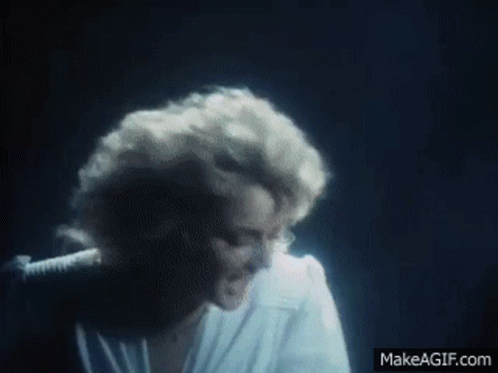 Woman in White Shirt Singing into Microphone