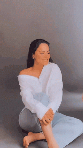Woman In White Shirt Sitting Cross-Legged Eyes Closed GIF
