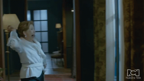 Woman in White Shirt Standing in Front of Nuestra Tele Window