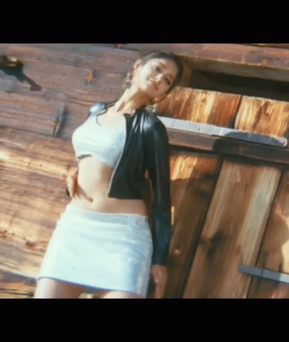 Woman in White Skirt and Black Jacket at Wooden Building