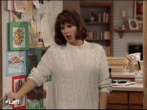 Woman in White Sweater in Front of Door With Laff