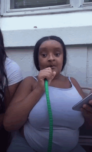 Woman in White Tank Top Drinking from Green Hose