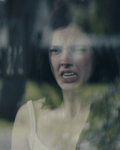 Woman in White Tank Top Making Funny Face at Window