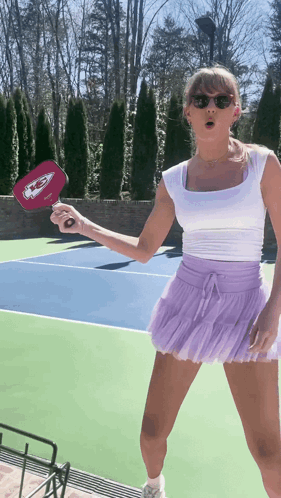 Woman in White Top and Purple Skirt Holding Chiefs Paddle