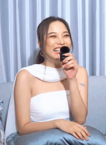 Woman in White Top Sitting on Couch Holding Brush in Mouth