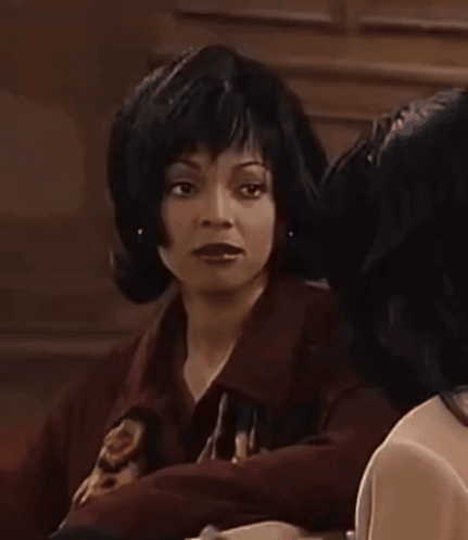 Woman in Wig Beside Woman in Dark Room