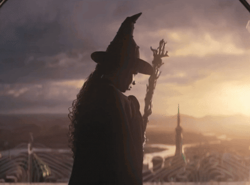 Woman in Witch Hat Holding Wand at Sunset