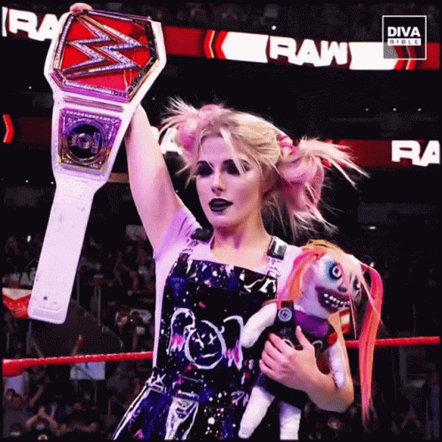 Woman In Wrestling Ring Holding Doll And Championship Belt GIF