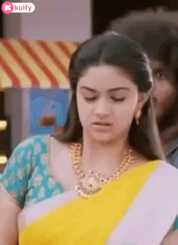 Woman In Yellow And White Saree With Gold Necklace Looking Down GIF