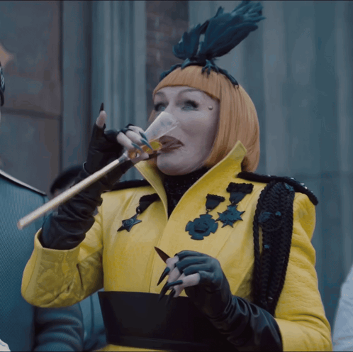 Woman in Yellow Coat and Black Gloves Drinking from Glass