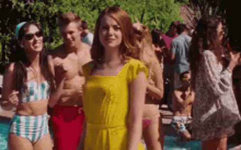 Woman In Yellow Dress Standing In Front Of Pool With Crowd GIF