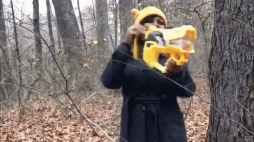 Woman in Yellow Hat Holding Toy Gun in Woods