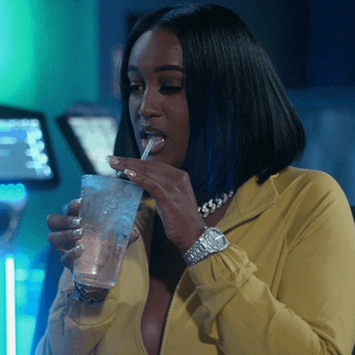Woman In Yellow Jacket Drinking From Glass With Straw GIF