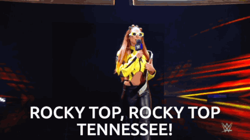Woman in Yellow Jacket Holding Microphone Saying Rocky Top Tennessee