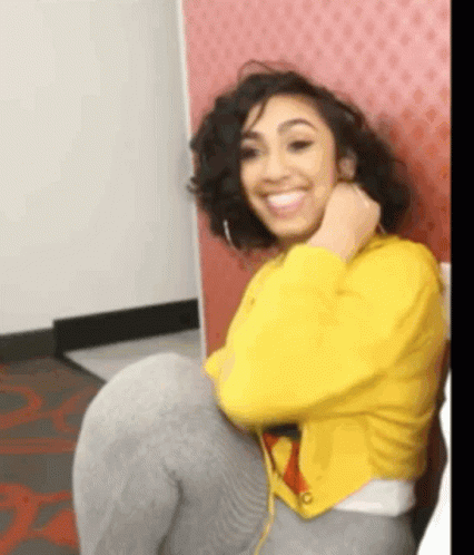 Woman In Yellow Jacket Sitting On Chair Smiling GIF