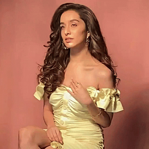 Woman in Yellow Off-Shoulder Dress Sitting on Pink Background