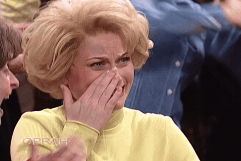 Woman in Yellow Shirt Covering Mouth With Oprah Behind