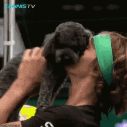 Woman Kissing Small Dog's Cheek at Tennis TV Logo