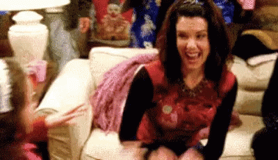 Woman Laughing And Waving On Couch GIF