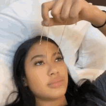 Woman Laying in Bed Holding Necklace