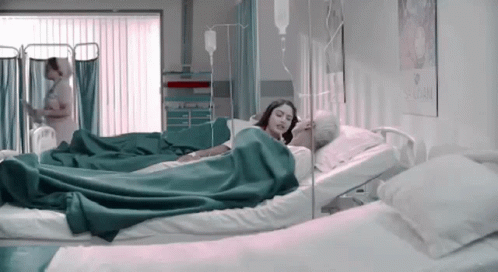Woman Laying In Hospital Bed Next To Older Man With IV GIF