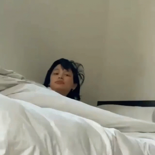 Woman Laying On Bed Making Funny Face GIF