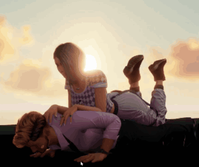 Woman Laying on Man's Lap With Sun Behind Them