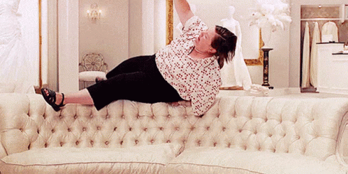 Woman Laying On White Couch With Arms Up GIF