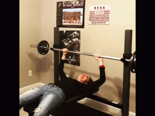 Woman Lifting Barbell in Front of We Make Marines Poster