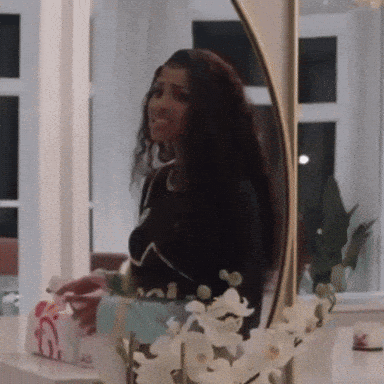 Woman Looking At Herself In Mirror With Flowers GIF
