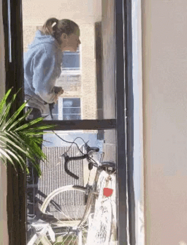 Woman Looking Out Window At Bike GIF