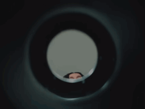 Woman Looking Through Hole in Wall