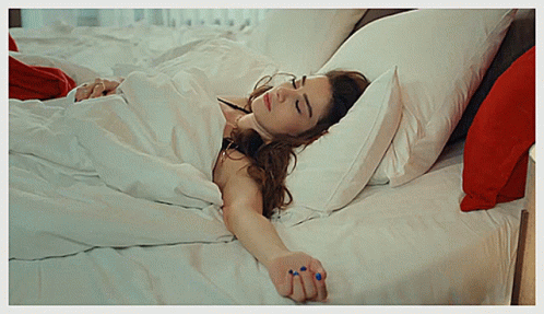 Woman Lying on Bed with White Sheets and Red Pillows