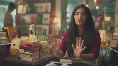 Woman Making Funny Face In Front Of Books GIF