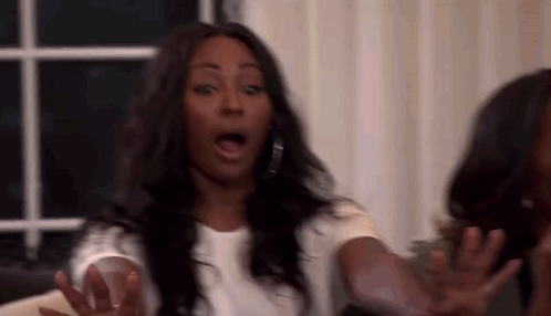 Woman Making Funny Face On Couch With Hands Outstretched GIF