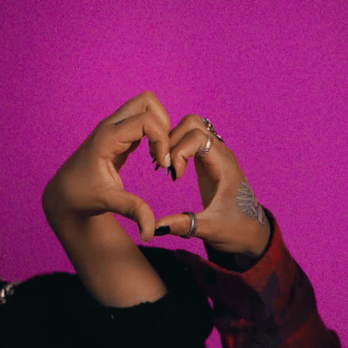 Woman Making Heart Shape on Pink Background