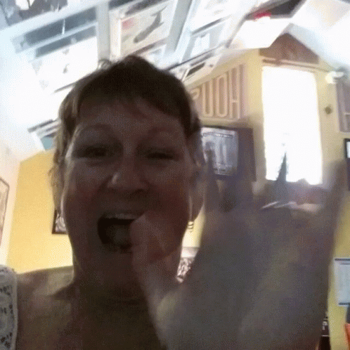 Woman Making Horns Sign In Front Of Home Sign GIF