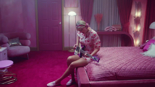 Woman on Bed Playing Guitar in Pink Room