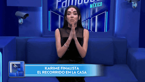 Woman on Blue Couch with Sign Karime Finalista