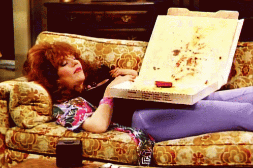 Woman on Couch Holding Pizza Box Saying LS