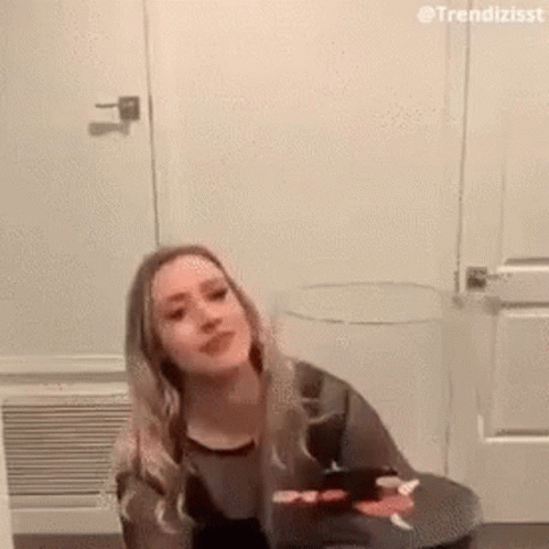 Woman On Stool By Door Looking At Camera GIF