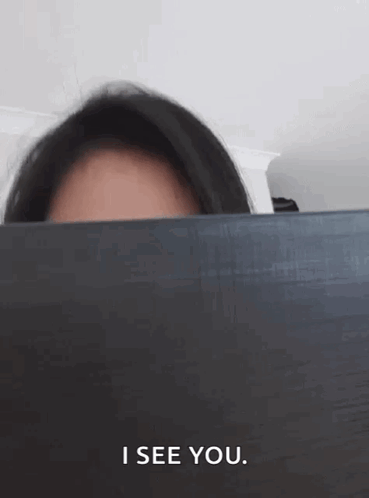 Woman Peeking Behind Laptop Saying I See You