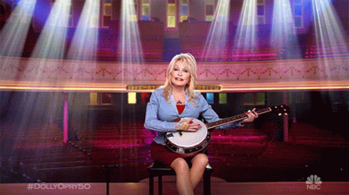Woman Playing Banjo On Chair With NBC Logo
