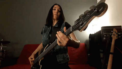Woman Playing Fender Bass Guitar on Red Couch