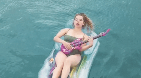 Woman Playing Guitar In Center Of The Pool GIF