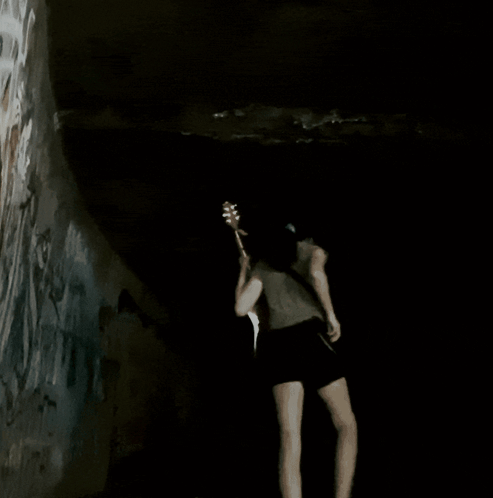 Woman Playing Guitar in Dark Room