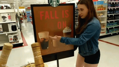 Woman Pointing at Starbucks Fall Is On Sign
