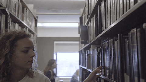 Woman Reading Book Inside Library GIF