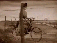 Woman Riding Bicycle On Dirt Road Black And White GIF